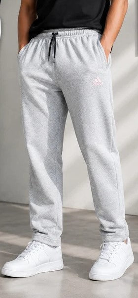 Light gray heather sweatpants with a small pink Adidas logo on the left thigh, worn by a model with white sneakers.