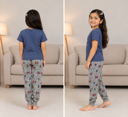 A child model shown in a split front-and-back view wearing a blue short-sleeve pajama top and gray patterned pajama pants in a living room setting.