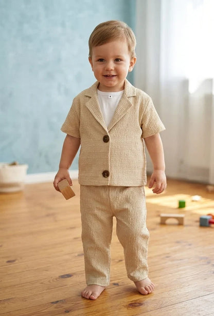beige textured short-sleeve button-front jacket over a white top and matching beige pants.